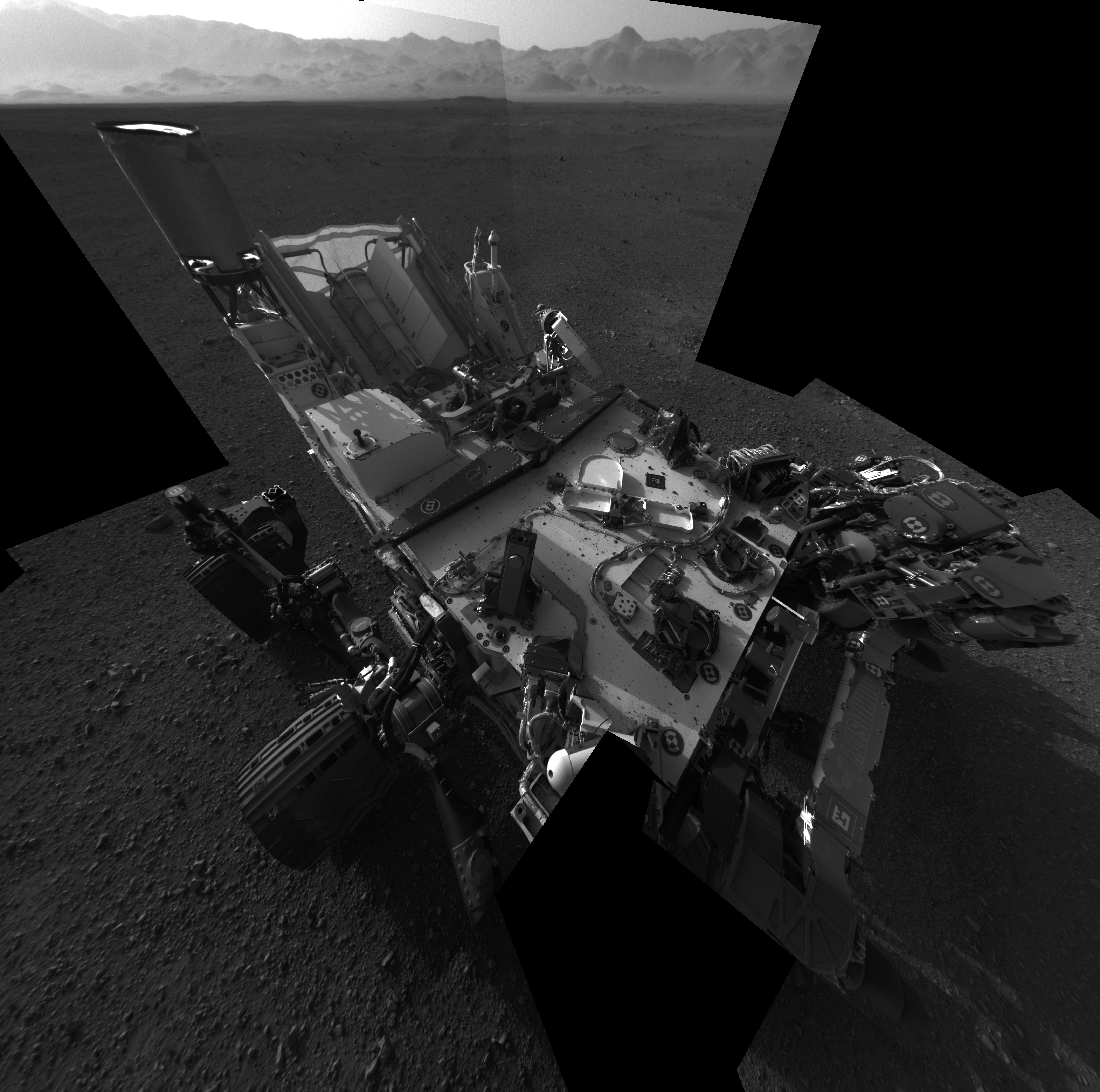 
Selvportrett av Curiosity, NASAs nyeste marsbil. Bakenden på bilen ses øverst til venstre og to av kjøretøyets høyre hjul ses også til venstre. Den kuperte kanten til Gale-krateret er synlig som en lys stripe i bakgrunnen. Noen grusbiter er også synlige oppå marsroveren. Bildet er tatt 7. august 2012.Lambdatrykk (NASA/JPL-Caltech)